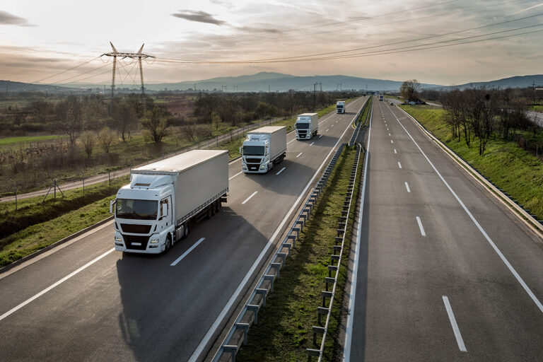 A row of trucks driving at a highway.